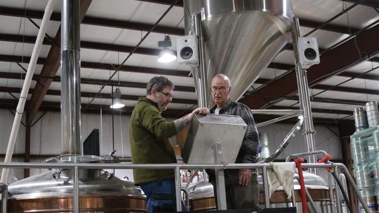 Two men in brewery looking thoughtful at screen